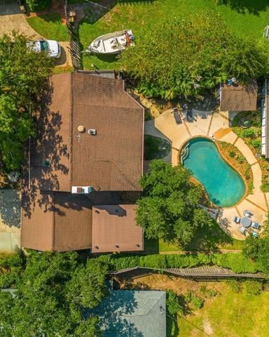 Aerial view of brick house with curved pool, surrounded by mature trees and green lawn