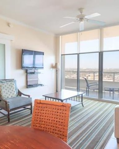 High-rise apartment living room with striped area rug, upholstered seating, and floor-to-ceiling windows overlooking cityscape