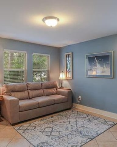 Blue-walled living room with brown sofa, desk, windows, and wood entry door