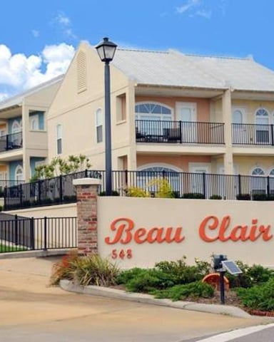 Beau Clair residential building with cream-colored facade, multiple balconies, and black iron fence entrance gate