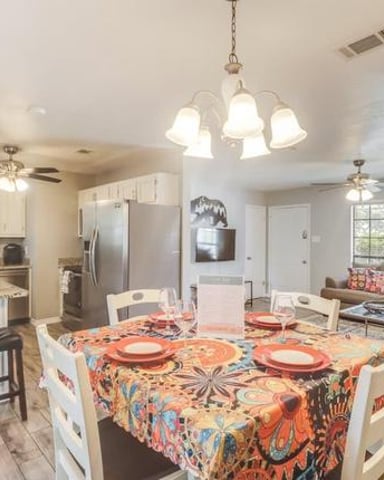 Open-plan kitchen and living room with round dining table, colorful tablecloth, and beige cabinetry