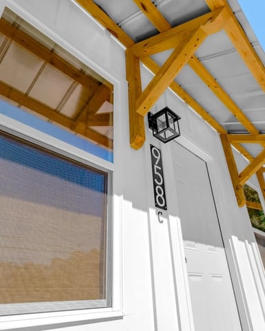 Modern white house exterior with yellow wooden pergola, large window, and address number 258